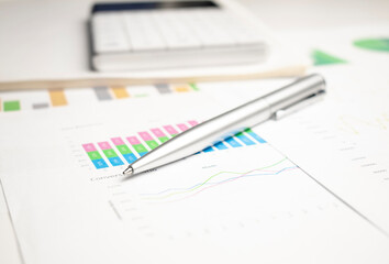 closeup blue graph and chart reports and pen on office table, financial and business concept
