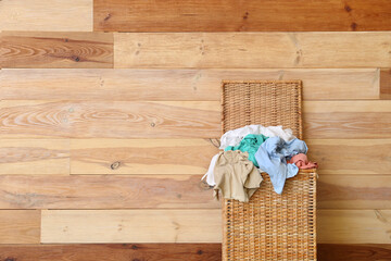 Wicker basket with dirty clothes near wooden wall