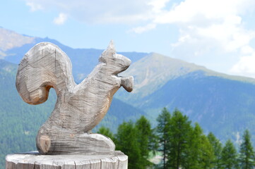 A wooden squirrel and mountains behind in Southtyrol 