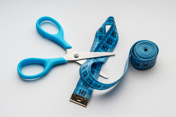 Scissors with blue handles cut the blue measuring tape. Diet, fitness, concept