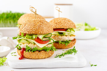 Chicken hamburgers, sandwich with chicken burger, cheese, tomato, cucumber, fresh lettuce, microgreen and ketchup on white background.