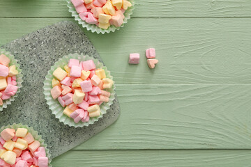 Forms with tasty marshmallows on color wooden background