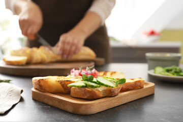Obraz na płótnie Canvas Board with tasty vegetarian bruschettas on table in kitchen, closeup