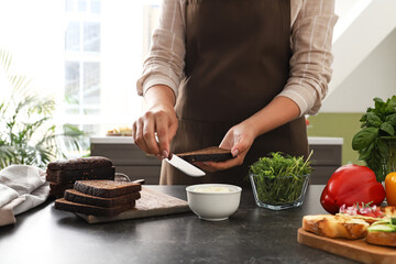 Woman cooking tasty bruschettas at table in kitchen