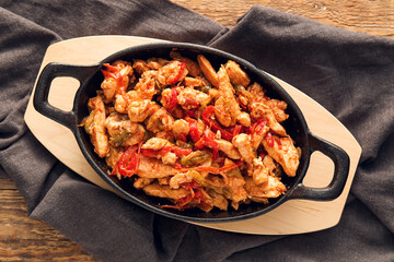 Frying pan with delicious chicken Fajita on wooden background