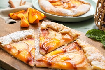 Board with pieces of tasty peach galette on table, closeup