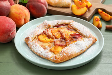 Plate with tasty peach galette on color wooden background, closeup