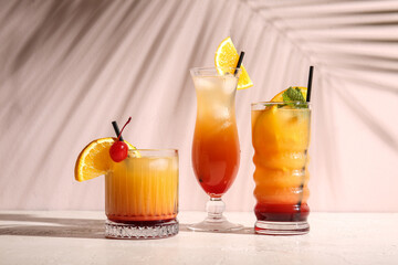 Glasses of tasty Tequila Sunrise cocktail on light background