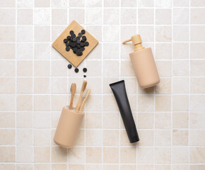 Black toothpaste with activated carbon, pills, brushes and soap on bath tile background