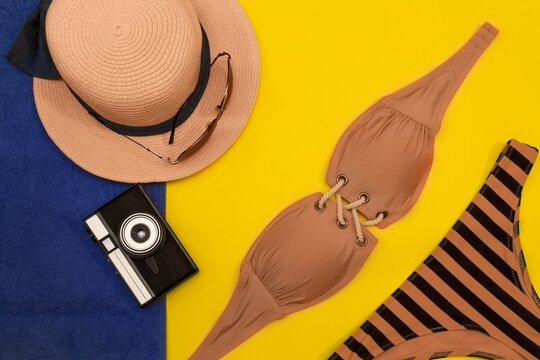 Summer vacation concept. Swimsuit, sunglasses, hat and camera on a yellow-blue background.