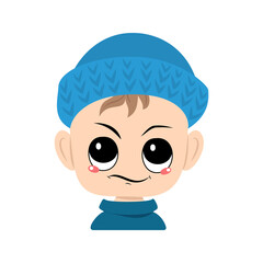 Boy with emotions of suspicious, displeased eyes in blue knitted hat. Cute kid with annoyed expression in autumnal or winter headdress. Head of adorable toddler