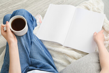 Woman with blank magazine and cup of tea on light background