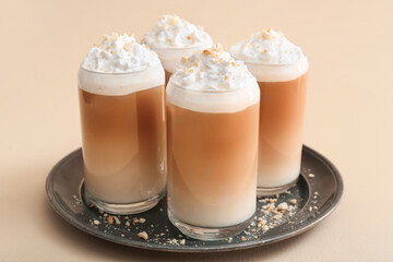 Glasses of tasty latte with nuts on beige background