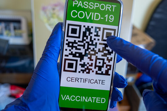 A person with surgical gloves on his hands shows his covid Passport on his smartphone screen.