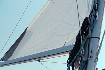 Fototapeta premium Open sail on blue sky, ropes, lines, catching wind, mast details