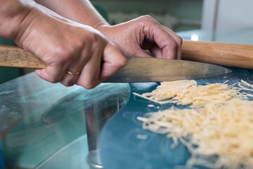 An unrecognizable woman cuts noodles. women's hands close-up
