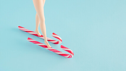 Creative skiing arrangement made of Christmas sticks and legs on a pastel blue background. Minimal New Year concept with copy space.