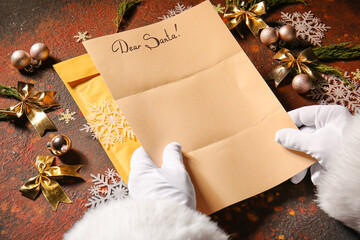 Hands of Santa Claus with empty letter on color background