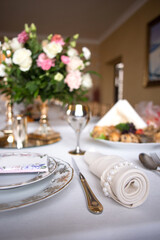 beautifully decorated festive table with plates and glasses and a bouquet of flowers in a restaurant