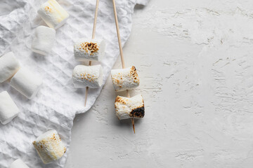 Skewers with delicious grilled marshmallow on light background