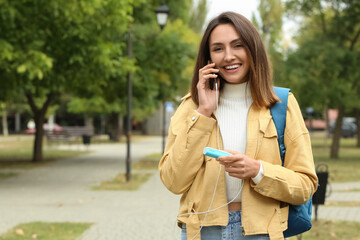 Young woman with phone and power bank outdoors