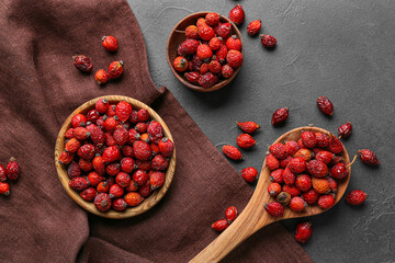 Bowls and spoon with fresh rose hip berries on black background