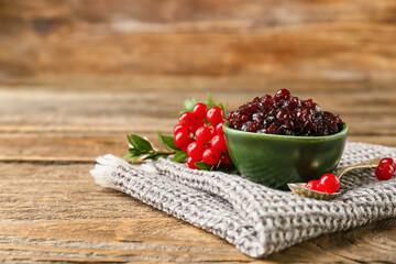 Bowl of tasty lingonberry jam and fresh berries on wooden background