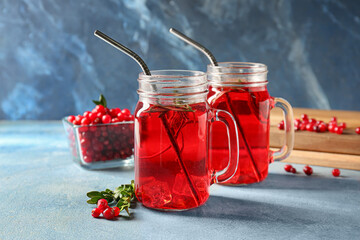 Mason jars of tasty lingonberry tea on table