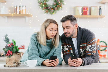 Man and woman at home looking at mobile phones spending time on social networks, Christmas and New Year