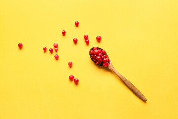 Spoon with ripe lingonberry on color background