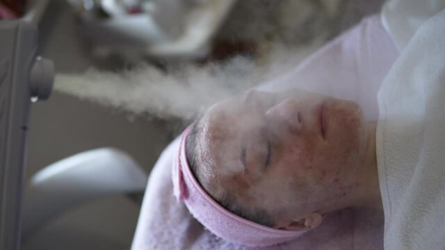 Beauty treatment of woman's problematic acne face skin ozone facial steamer in spa center, steam for smooth skin and skin treatment