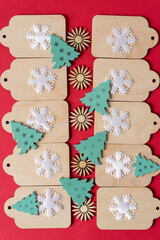 wooden tags with flat wooden christmas tree and starburt shapes arranged on a red paper background