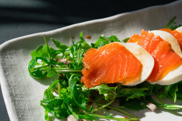 Fresh homemade healthy keto smoked salmon fish seafood salad with tasty buffalo mozzarella cheese Italian balsamic vinegar bio organic rocket arugula with olive oil for dinner lunch breakfast meal