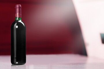 The unopened bottle of red wine on the desk