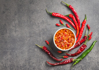 Chili olie saus chili pepers vlokken in olie donkere achtergrond kopie ruimte. Pittige specerij.
