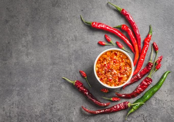 Fotobehang Chili olie saus chili pepers vlokken in olie donkere achtergrond kopie ruimte. Pittige specerij. © travelbook