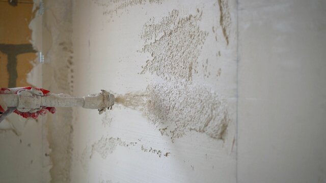 Machine application of plaster to the wall. Plasterer throws plaster on the wall. Plastering walls in a new house. Machine application of mortar to the wall.