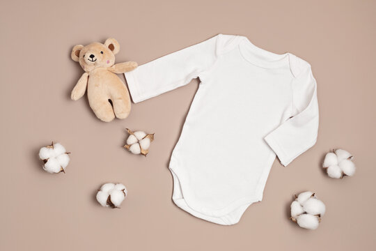 Mockup of white infant bodysuit made of organic cotton with eco friendly baby toys. Onesie template for brand, logo, advertising. Flat lay, top view