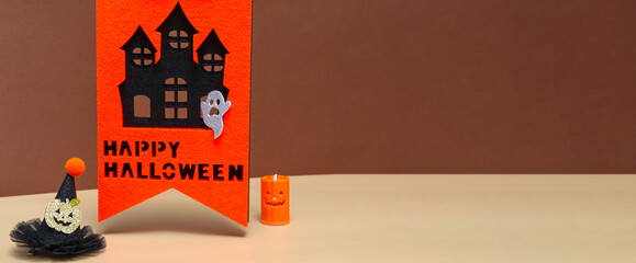 Halloween concept with haunted house, candle and witch hat on colored background.