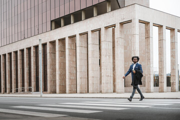 Big long shot of young african businessman crossing the street with happiness, space for copy