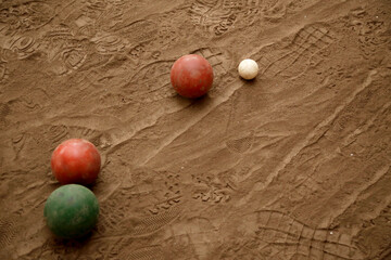 Bocce ball game. Classic outdoor game on a sand floor and played with balls and a bochin or small ball. Sport for older adults. Close up. Sand floor with marked footprints and bowls.