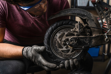 An mechanic holding the electric scooter wheel in place with both hands. © Guillermo Spelucin