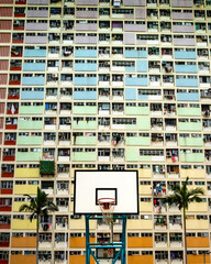 Fototapeta na wymiar basketball court and palm trees in front of colorful apartment building