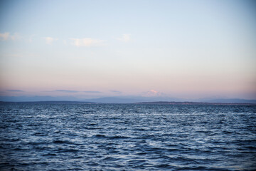 Shot of mount baker in a distant pink sky with the ocean in the foreground