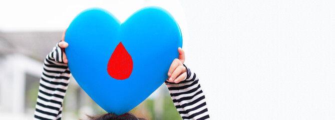 Light blue heart on kid hand with blood banner background.World diabetes day.Diabetes on kid.Heart danger insulin.Family support for child.blood cells donation world.World Aids day.November Diabetes.
