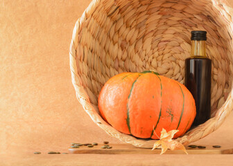 Still life with pumpkin and a bottle of pumpkin oil in a wicker basket