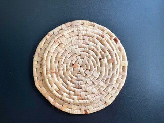 Round shape woven placemat on black background, handmade kitchenware made from dried water hyacinth, weave craft product