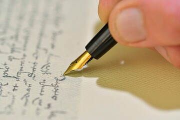 Antique style. Hand writing letter with fountain pen. Close-up of a male hand ready to write with...