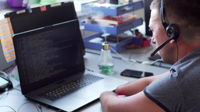 A caucasian man in headphones with amputated two stump hands and legs works online at the laptop in office. A man with a disability in earphones works in call-center at the laptop
