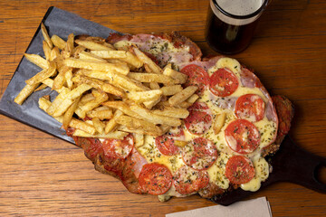 Neapolitan Milanese with mozzarella and sliced tomato garnished with French fries and beer on...